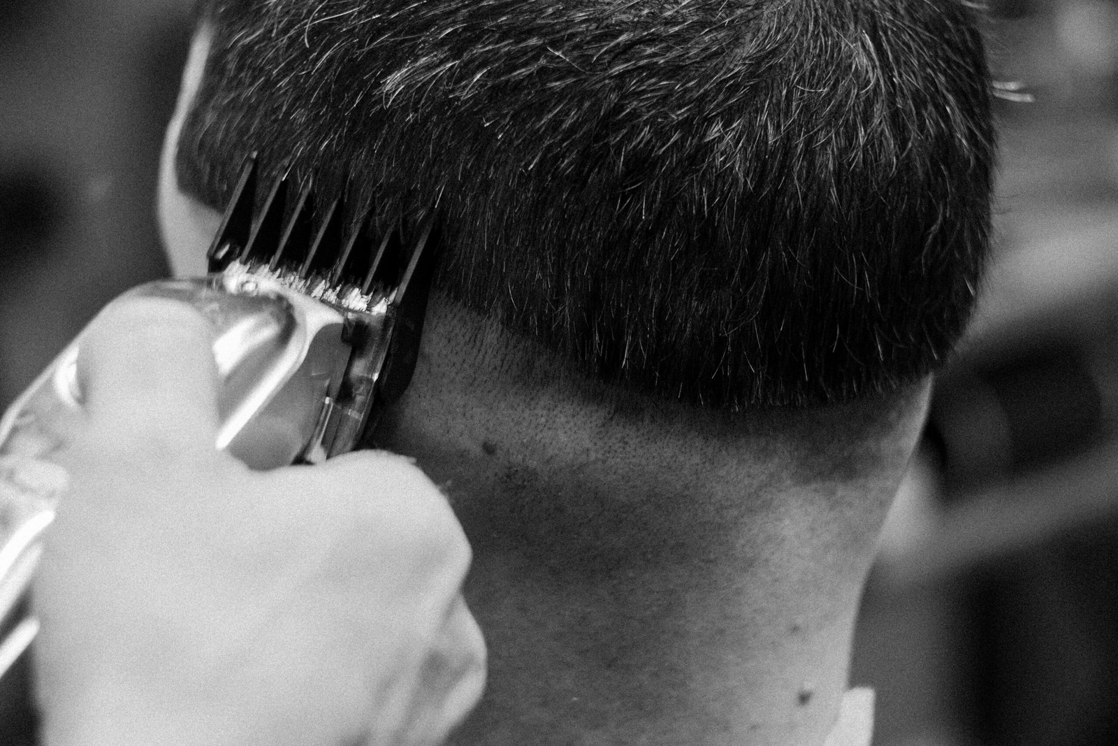 Close-up of a barber giving a haircut with clippers in a classic black and white theme.