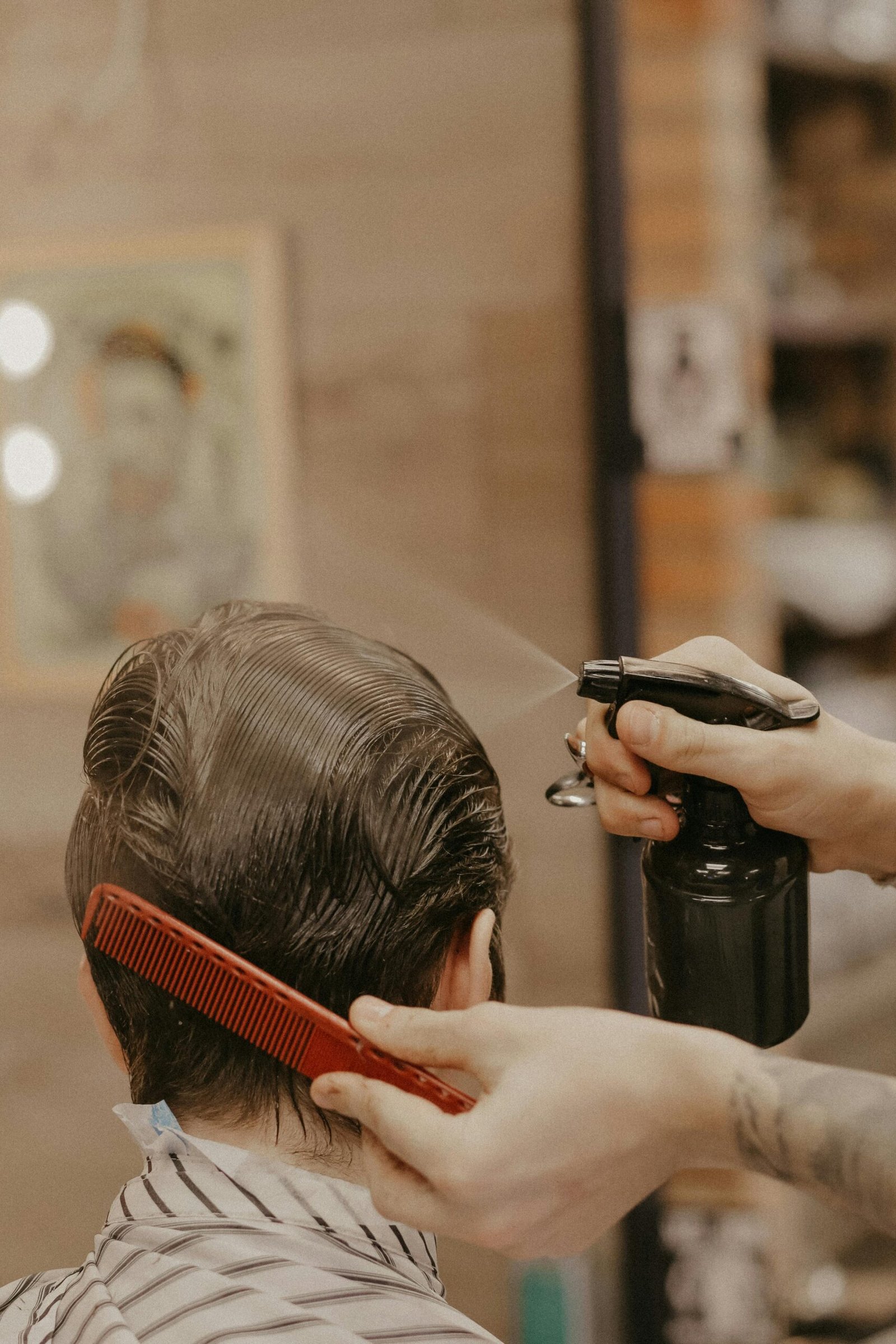 Hairstylist using a comb and spray bottle while styling men’s hair
